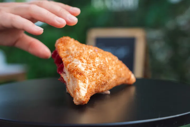 a close up of a hand holding a half eaten sandwich on a plate
