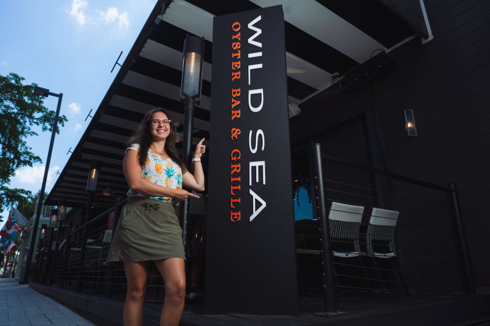 a person standing in front of a Wild Sea Sign